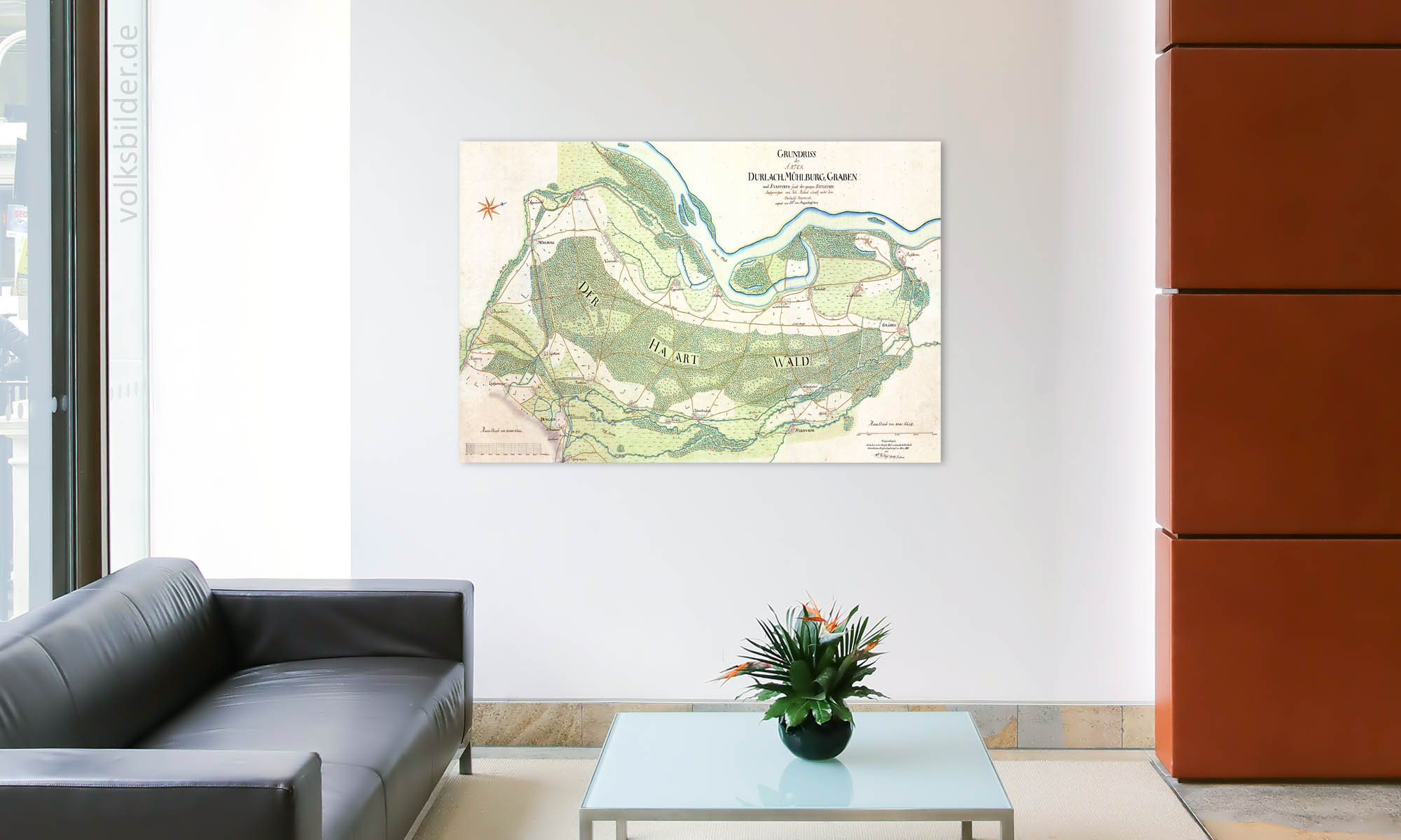 Foto eines Wartebreiches mit Couch und Couchtisch. An der Wand im Hintergrund hängt ein Wandbild mit einer handgezeichneten Landkarte der Region zwischen Durlach, Mühlburg und Graben von 1714.