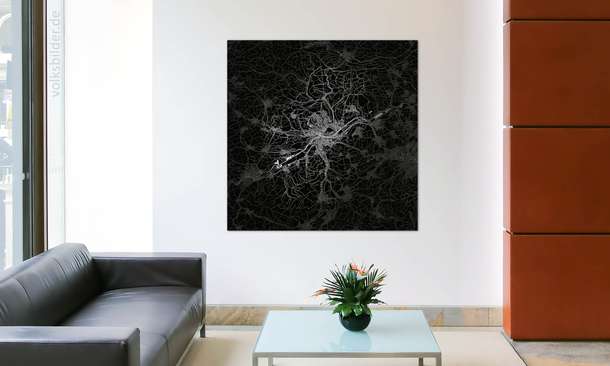 Foto vom Foyer einer Firma. Neben einer schwarzen Ledercouch steht ein Couchtisch. Im Hintergrund an der Wand hängt ein Bild mit einer in Schwarzweiß gehaltenen Landkarte von Tübingen.