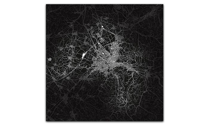 Ein quadratisches Wandbild, das eine Karte vom Stadtgebiet von Freiburg und der näheren Umgebung zeigt. Karteninhalte wie Straßen, Gebäude und Gewässer sind weiß dargestellt vor tiefschwarzem Hintergrund.